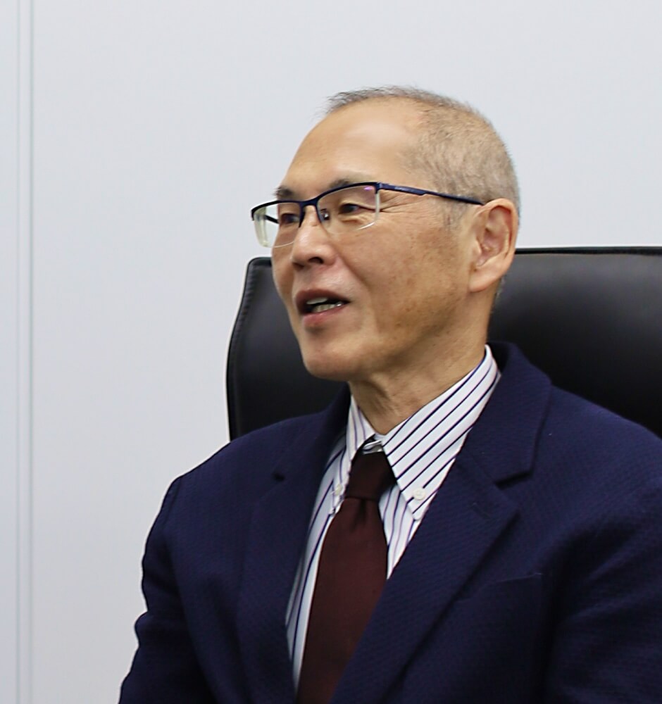 スーツ姿で椅子に腰掛けた代表取締役社長